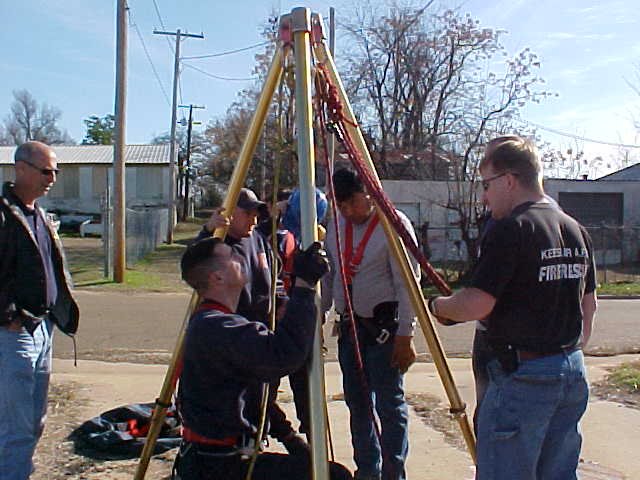 Fire fighters strapping into the rigging to get them down the manhole.